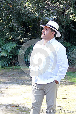 Dark-skinned Latino 50 year old man dressed in guayabera and hat, traditional Latin American dress, enjoys a walk outdoors Stock Photo