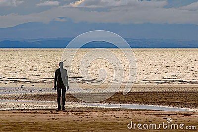 A Silhouette figure facing the horizon at Crosby Beach,England Stock Photo