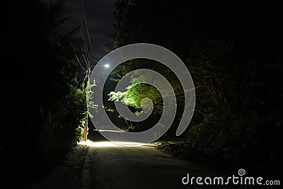 dark street with dirt road illuminated by light Stock Photo