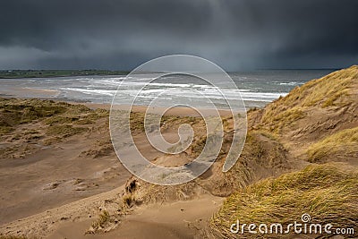 Dark strorm clouds over ocean and sand dune. Stock Photo