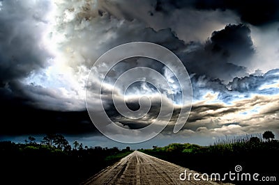 Dark thunder clouds and dramatic storms over a rural road. Stock Photo