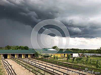 Dark thundercloud hung over the farm in the village. Dramatic countryside landscape Stock Photo