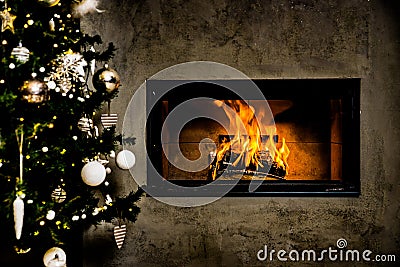 Dark wall with dark Christmas tree with shining fireplace and white christmas decoration Stock Photo