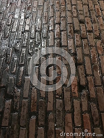 Dark wet slipper worn brick paved road Stock Photo