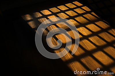 Dark window bars shadow on the wooden floor in prison Stock Photo