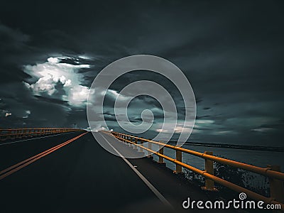 A darkness road across a bridged onto a river Stock Photo