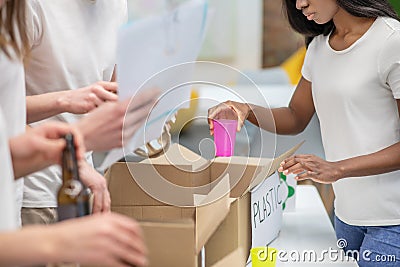 Darkskinned girl sorting used plastic into box Stock Photo