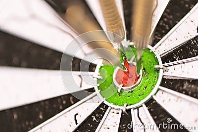 Darts arrows in the target center. Dart in bulls eye of dartboard with shallow depth of field Stock Photo