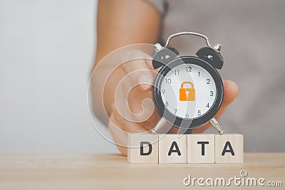 DATA, text on wooden cube, with hand holding black analog alarm clock and key locked on dial for personal data security concept Stock Photo