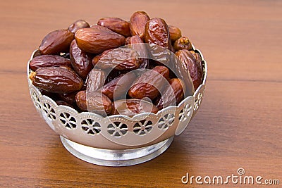 Dates fruit on silver bowl on wooden table. The Muslim feast of the holy month of Ramadan Kareem Stock Photo