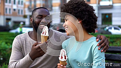 Dating couple eating ice-cream, sitting on city bench, having fun together, love Stock Photo