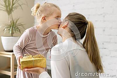 daughter giving present and kiss to her mom at home. birthday, womens day or mothers day concept Stock Photo