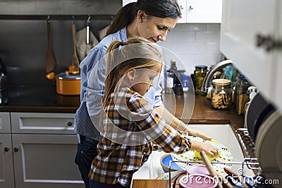 Daughter helping mom in cleaning dishes Stock Photo
