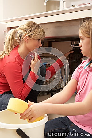 Daughter Helping Mother To Mop Up Leaking Sink Stock Photo