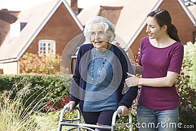 Daughter Helping Senior Mother To Use Walking Frame Stock Photo