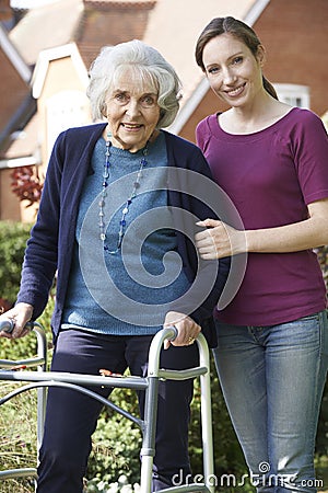 Daughter Helping Senior Mother To Use Walking Frame Stock Photo