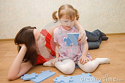 Daughter and her mother are solving puzzle Stock Photo