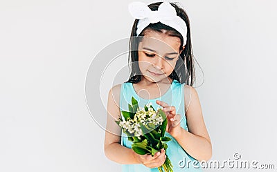 Daughter holds the bouquet of white flowers for her mother. Cute kid holds a bouquet and looking to flowers posing on white Stock Photo