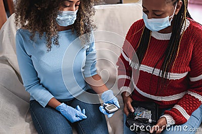 Daughter making blood glycemia test for diabetes check during lockdown isolation - Focus on senior woman Stock Photo