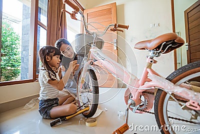 Daughter and mother have fun installing their new bicycle basket Stock Photo