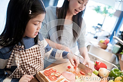 Daughter and mother preparing the sandwich and salad for breakfast in kitchen. Stock Photo