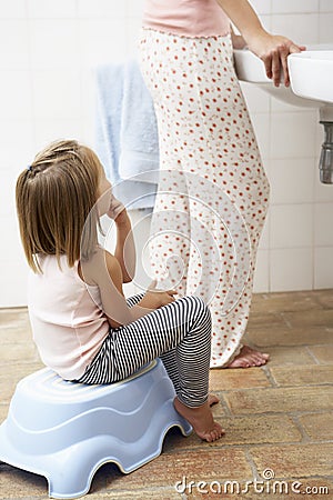 Daughter Reluctant To Brush Teeth With Mother Stock Photo