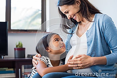 Daughter touching the belly of her pregnant mother Stock Photo