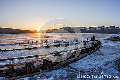 At dawn skeleton of a ship frozen in the ice on the shore Stock Photo