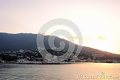 Dawn of the sun on the sea, in the port of the city of Yalta, with a view of the houses and mountains. Crimea, Ukraine, background Editorial Stock Photo