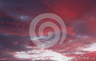 Pretty red and purple skies at daybreak, with large puffy clouds opening up for the sunny day ahead Stock Photo