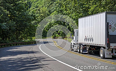 Day cab local freight big rig semi truck transporting cargo in dry van semi trailer with lifting platform on the back driving on Stock Photo