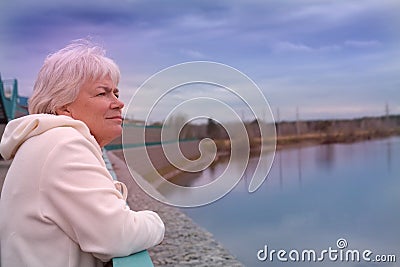 Day dreaming senior woman outdoors. Contented senior woman looking thoughtful during walking countryside Stock Photo