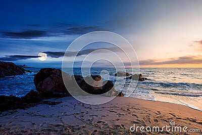 Day and night time change concept above huge stones on the sandy beach at twilight Stock Photo