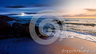 Day and night time change concept above huge stones on the sandy beach at twilight Stock Photo