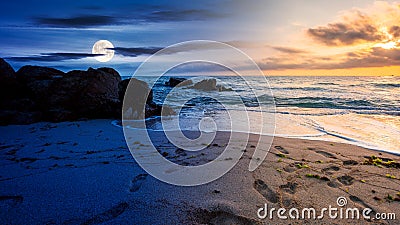 Day and night time change concept above huge stones on the sandy beach at twilight Stock Photo