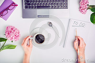 Day Planning - female hands with cup of coffee and pencil write To do list on the white working office desk with laptop, notebook, Stock Photo