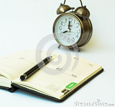 Day timer organizer with a pen and a mechanical alarm clock, time management and activity planning concept Stock Photo