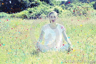 Daydreaming young yoga woman sitting on grass with colorful dots Stock Photo