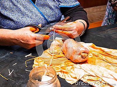 Working woman cutting a rope with scissors closing the gut of a pork loin Stock Photo