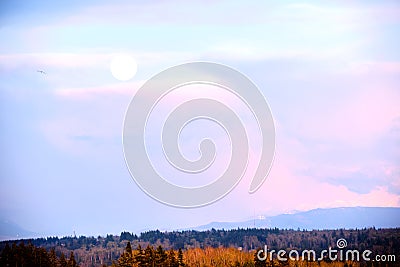 Daytime full moon rises over base of Mount Baker Stock Photo