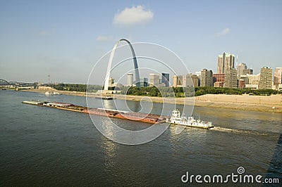 Daytime view of tug boat pushing barge down Mississippi River in front of Gateway Arch and skyline of St. Louis, Missouri as seen Editorial Stock Photo