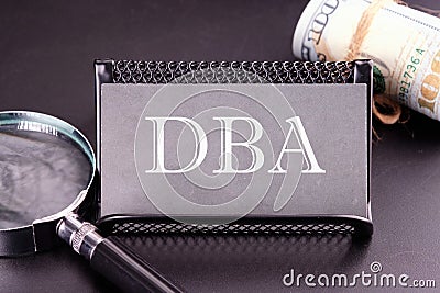 DBA text on the business card next to the money, a magnifying glass on a black background Stock Photo