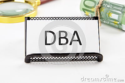 DBA the text on the business card next to the roll of money with a magnifying glass in the background is out of focus on a white Stock Photo