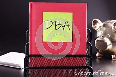 DBA text on a yellow sticker pasted on an upright diary on a black background Stock Photo