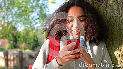 De gemengde tiener die van het ras Afrikaanse Amerikaanse meisje tegen een boom leunen die celtelefoon met behulp van stock video De gemengde tiener die van het ras Afrikaanse Amerikaanse meisje tegen een boom leunen die celtelefoon met behulp van stock video