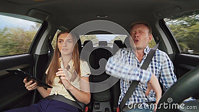 De grappige jongen die in de auto en het meisje dansen die de tablet gebruiken 4K stock videobeelden De grappige jongen die in de auto en het meisje dansen die de tablet gebruiken 4K stock videobeelden