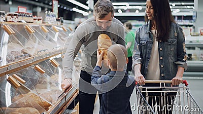 De nuttige zoon helpt zijn ouders om brood te kopen, opent de vader container en de jongen neemt brood en ruikt het stock footage De nuttige zoon helpt zijn ouders om brood te kopen, opent de vader container en de jongen neemt brood en ruikt het stock footage