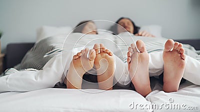 De vrouw en de man koppelen het liggen in bed die samen onder deken, nadruk op voeten slapen stock videobeelden De vrouw en de man koppelen het liggen in bed die samen onder deken, nadruk op voeten slapen stock videobeelden