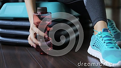 De vrouwenzitting in gymnastiek en neemt een fles met sporten drinkt in vorm van een domoor stock footage De vrouwenzitting in gymnastiek en neemt een fles met sporten drinkt in vorm van een domoor stock footage
