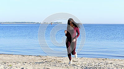 In de zomer, op de rivierbank, op het strand bij dageraad, een mooie vrouwenkunstenaar, in een strak kostuum, danst zij, springt stock videobeelden In de zomer, op de rivierbank, op het strand bij dageraad, een mooie vrouwenkunstenaar, in een strak kostuum, danst zij, springt stock videobeelden
